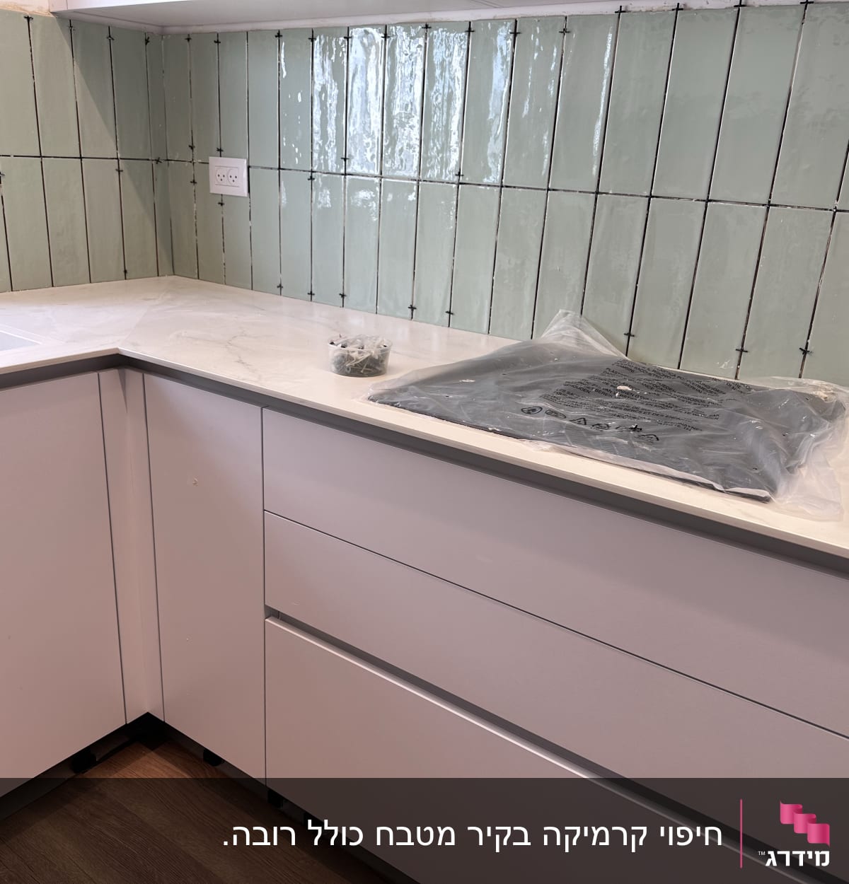 אריחים מותקנים על קיר מטבח במהלך שיפוץ